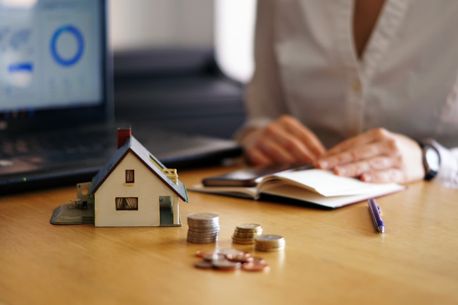 Une maison miniature et des pièces devant un dossier de financement